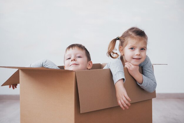 Hermanito y hermanita jugando en cajas de cartón en la guardería