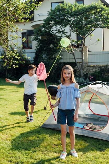 Hermano y hermana atrapar mariposas e insectos con red de mariposas en el parque