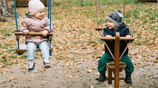 Hermano y hermana columpiándose en el parque