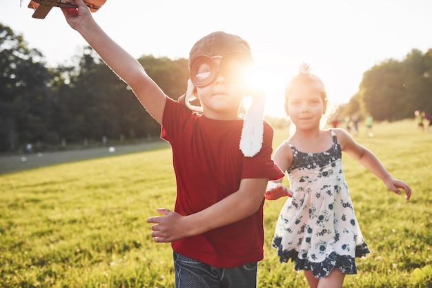 Hermano y hermana están jugando juntos. Dos niños jugando con un avión de madera al aire libre