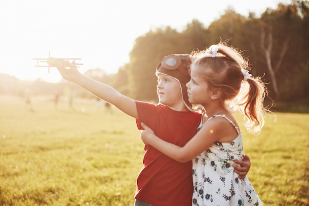 Hermano y hermana están jugando juntos. Dos niños jugando con un avión de madera al aire libre