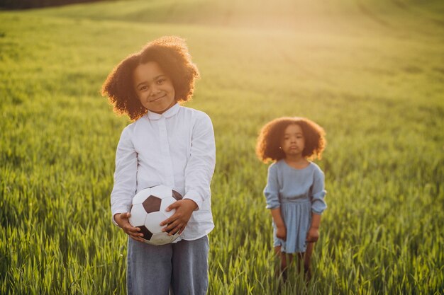 Hermano y hermana jugando con la pelota en el campo