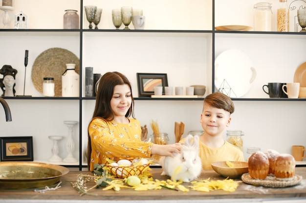 Hermano y hermana se preparan para la Pascua. Niño y niña vestidos de amarillo. Los niños recogen una canasta de Pascua.