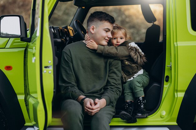 Hermano con hermanita sentada en coche verde