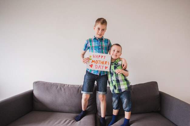 Hermanos alegres con un cartel para celebrar el día de la madre