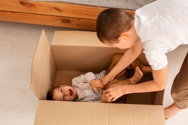 Foto gratuita hermanos de alto ángulo jugando con caja