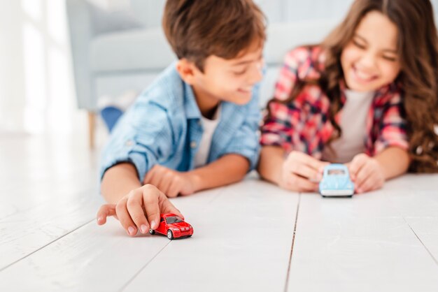 Hermanos de ángulo bajo en el piso jugando con juguetes