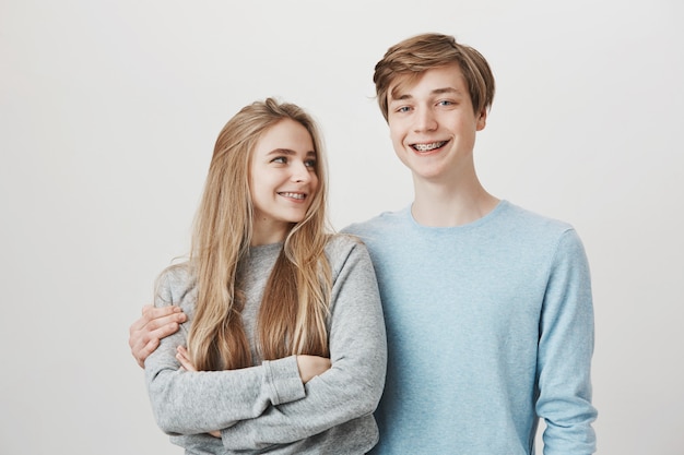 Hermanos cariñosos felices de pie juntos. Chica y chico sonriendo, abrazando