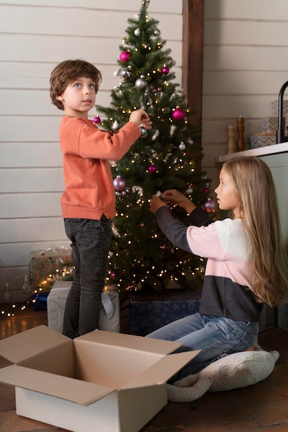 Hermanos decorando el árbol de navidad juntos