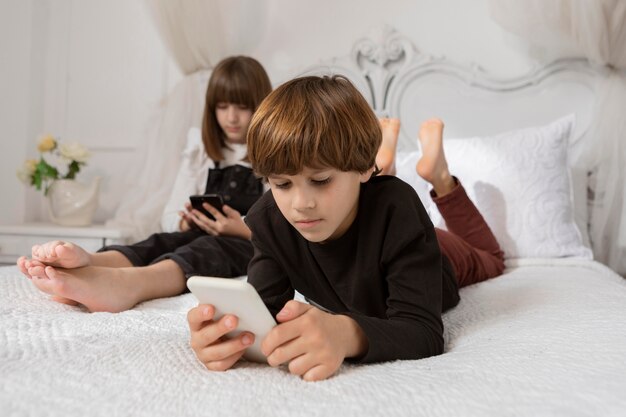 Hermanos en dormitorio con teléfono