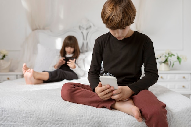 Hermanos en dormitorio con teléfono