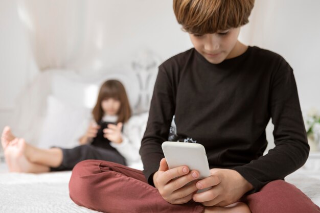 Hermanos en dormitorio con teléfono