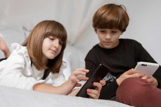 Hermanos en dormitorio con teléfono