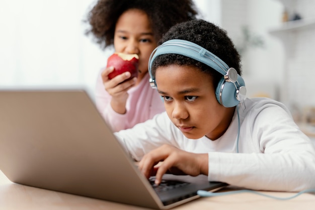 Hermanos escuchando música y usando laptop