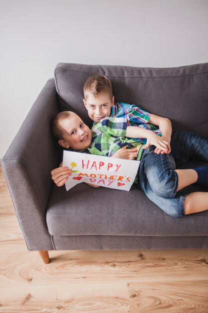 Hermanos felices con un cartel para el día de la madre