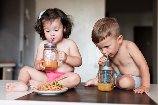 Hermanos jóvenes lindos bebiendo jugo