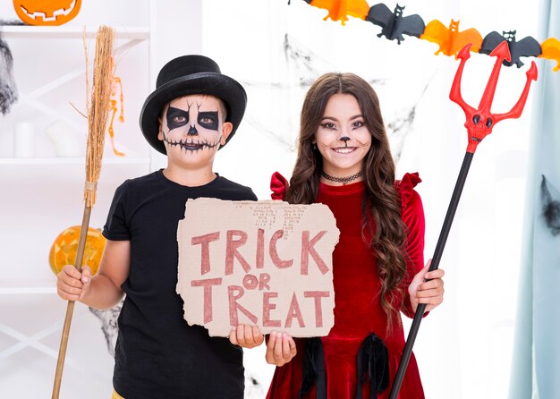 Hermanos lindos con cartel de truco o trato para halloween