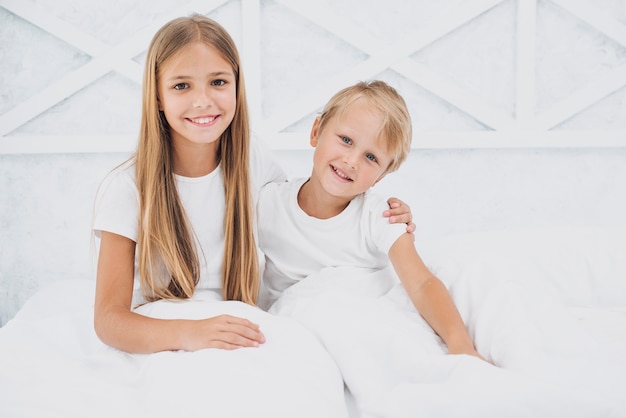 Hermanos quedándose en la cama mirando a la cámara