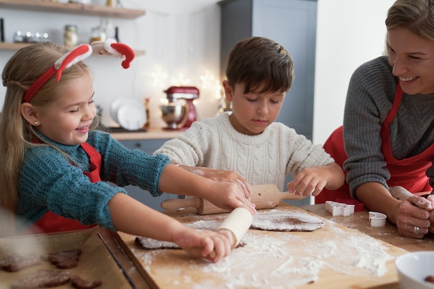 Foto gratuita hermanos rodando una masa de pan de jengibre