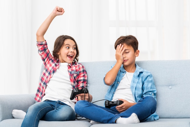 Hermanos en el sofá jugando con joystick