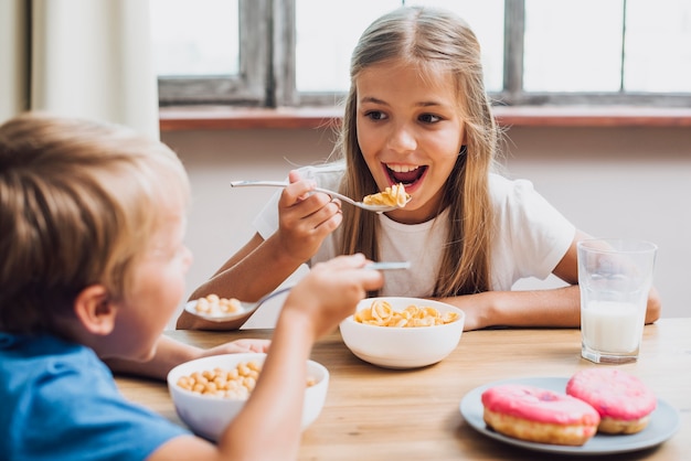 Hermanos sonrientes mirándose mientras comen