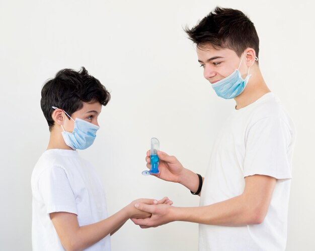 Hermanos con vista lateral usando desinfectante para manos