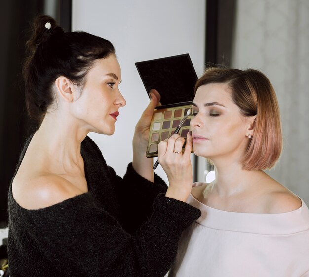 Hermosa artista aplicando maquillaje en modelo