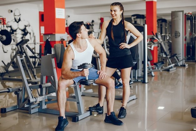 Una hermosa y atlética chica de ropa deportiva entrenando en el gimnasio con su novio