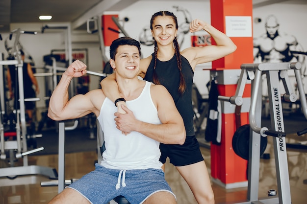 Una hermosa y atlética chica de ropa deportiva entrenando en el gimnasio con su novio