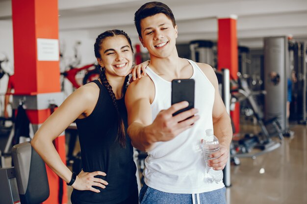 Una hermosa y atlética chica de ropa deportiva entrenando en el gimnasio con su novio