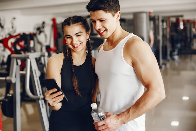 Una hermosa y atlética chica de ropa deportiva entrenando en el gimnasio con su novio