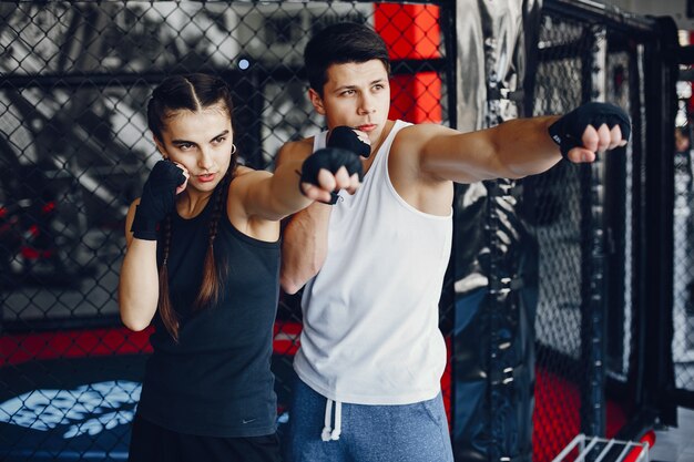 Una hermosa y atlética chica de ropa deportiva entrenando en el gimnasio con su novio