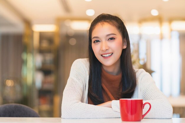 Hermosa y atractiva frescura femenina asiática sonrisa alegre mañana trabajando con café portátil desde casa con felicidad disfrutar de la vista al jardín mujer joven asiática con fondo de jardín de luz de ventana