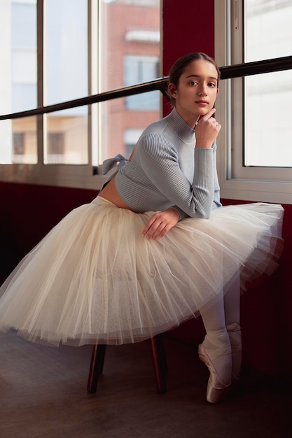 Hermosa bailarina en falda tutú posando junto a la ventana