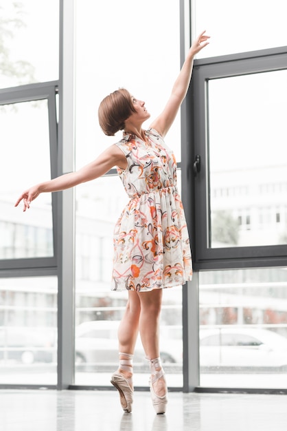Hermosa bailarina posando cerca de la ventana de vidrio