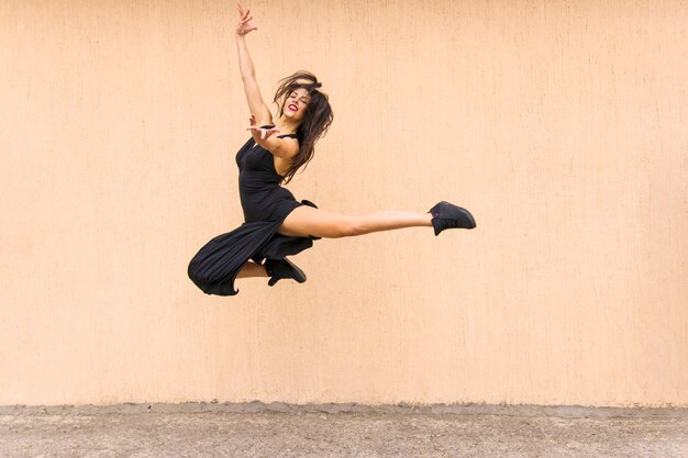 Hermosa bailarina de tango saltando en el aire contra el telón de fondo de la pared