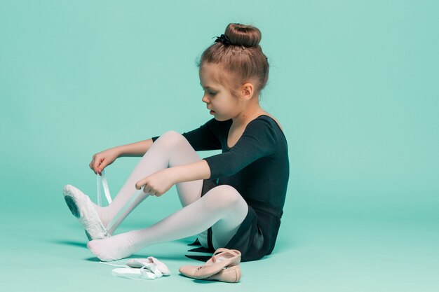 Hermosa bailarina en vestido negro para bailar poniéndose zapatos de punta