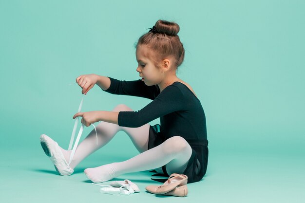 Hermosa bailarina en vestido negro para bailar poniéndose zapatos de punta