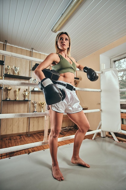 Una hermosa boxeadora fuerte posa para el fotógrafo mientras sostiene un casco protector.