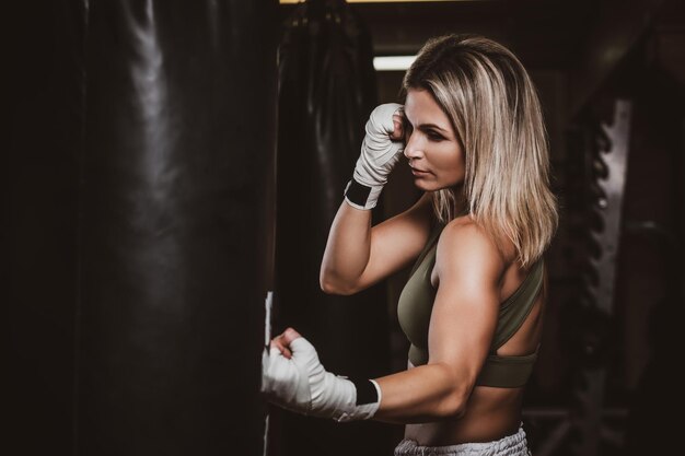 Hermosa boxeadora tiene su entrenamiento con saco de boxeo en el gimnasio.