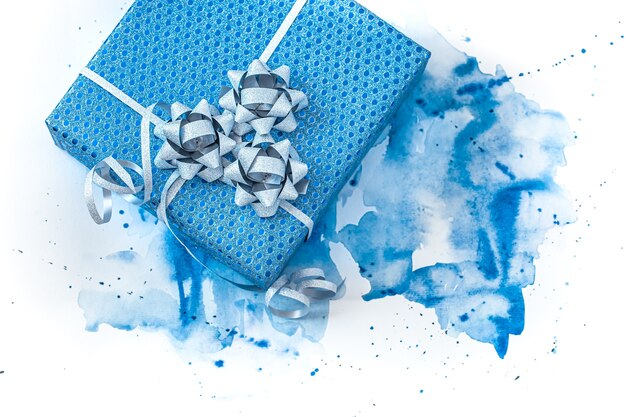 Hermosa caja de regalo azul sobre fondo de acuarela, elegante fondo creativo.