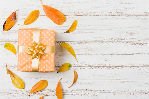 Hermosa caja de regalo y hojas de otoño sobre la mesa con espacio de texto