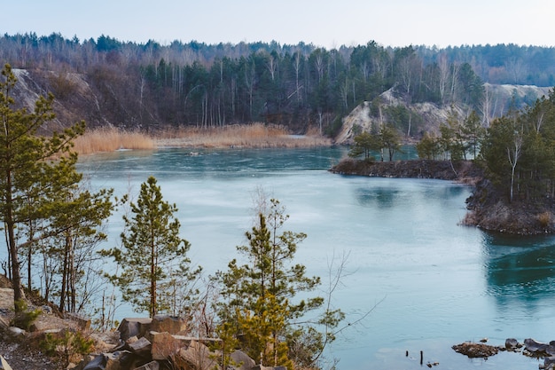 Hermosa cantera cerca del lago cubierto de hielo fino