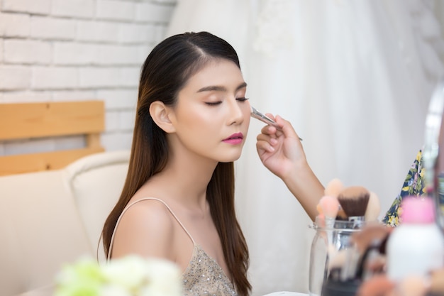 Hermosa cara de mujer y mano de maquillaje.