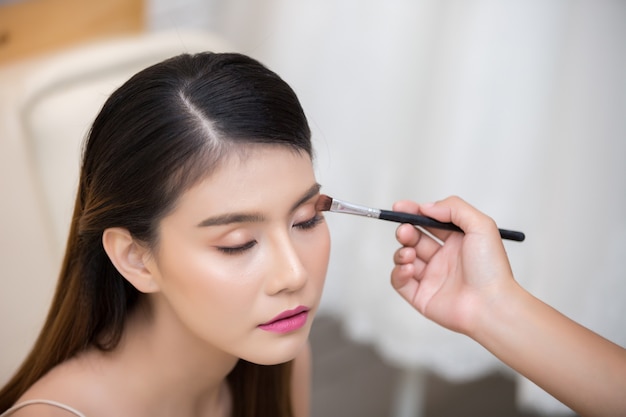 Hermosa cara de mujer y mano de maquillaje.