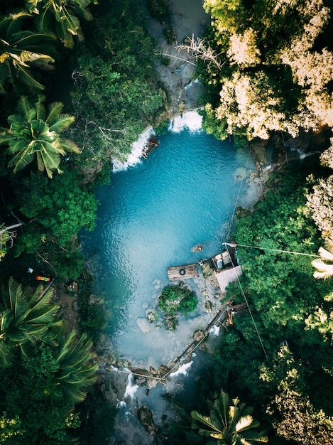 Hermosa cascada que fluye hacia el río rodeada de verdes