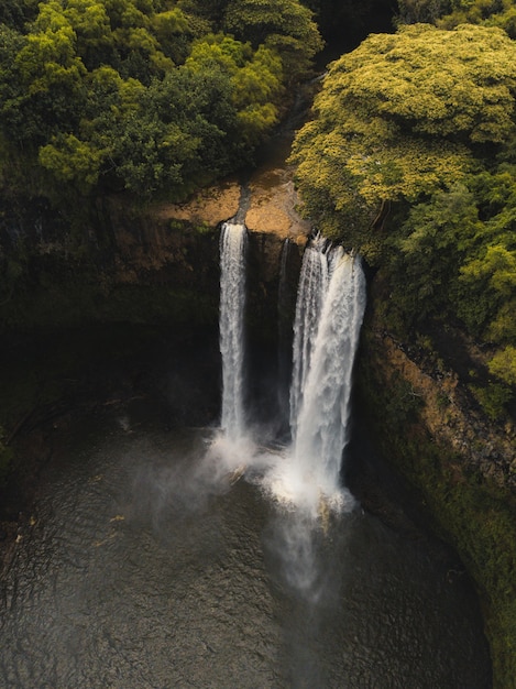 Hermosa cascada que fluye hacia el río rodeada de verdes