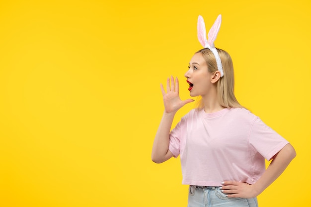 Hermosa chica adorable rubia de Pascua con orejas de conejo rosa y lápiz labial rojo llamando a alguien