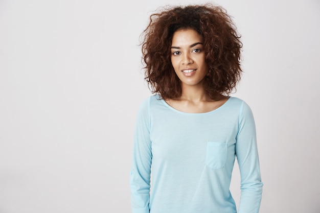 Hermosa chica africana en camisa azul sonriendo.