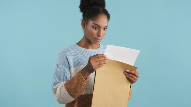 Hermosa chica afroamericana concentrada mirando atentamente los resultados de los exámenes sobre un fondo colorido